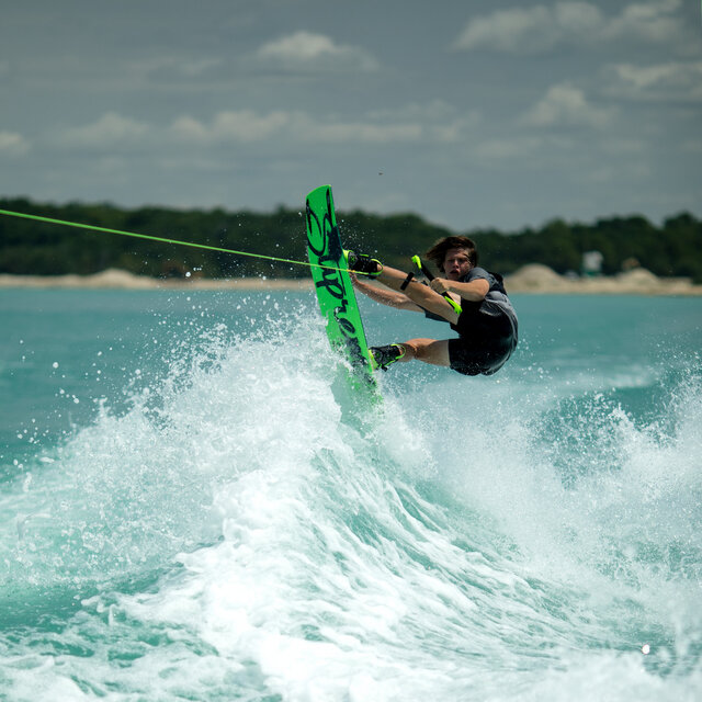 On top of a wake on a green wakeboard.