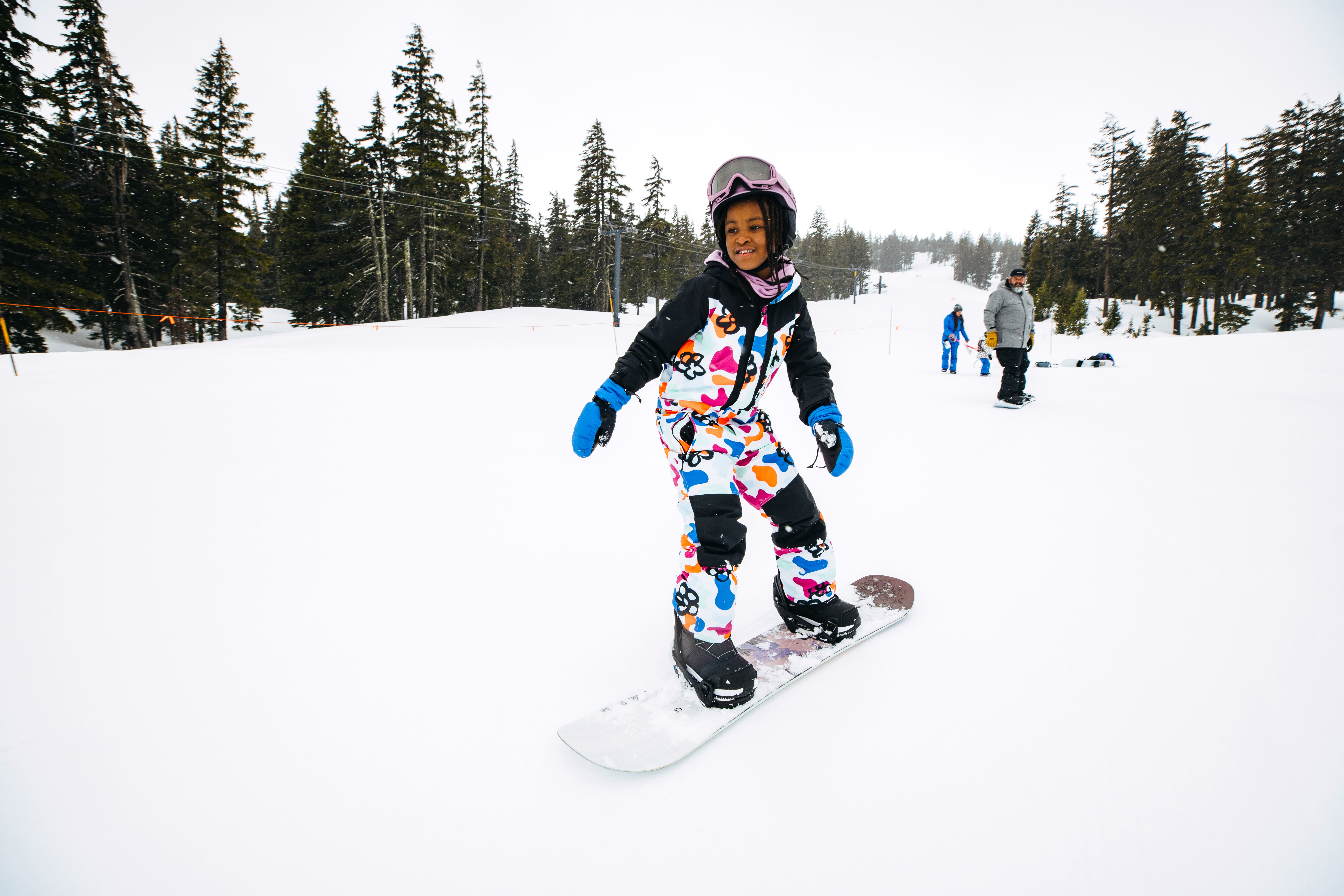 Young child on snowboard learning how to snowboard.
