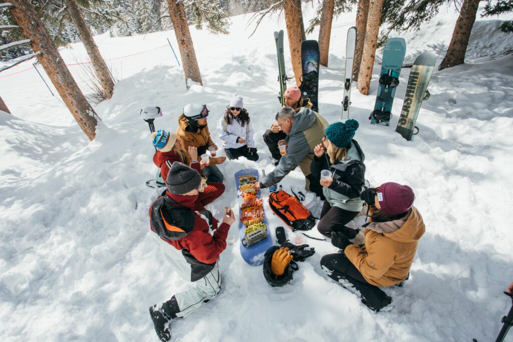 Charcuterski board on the snow with meats, cheeses, and fruit – après-ski snack idea for mountain picnics
